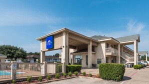 Un hôtel doté d’une piscine, d’un panneau indiquant que l’accès est réservé aux clients, et d’un panneau signalant l’établissement American Inn & Suites.