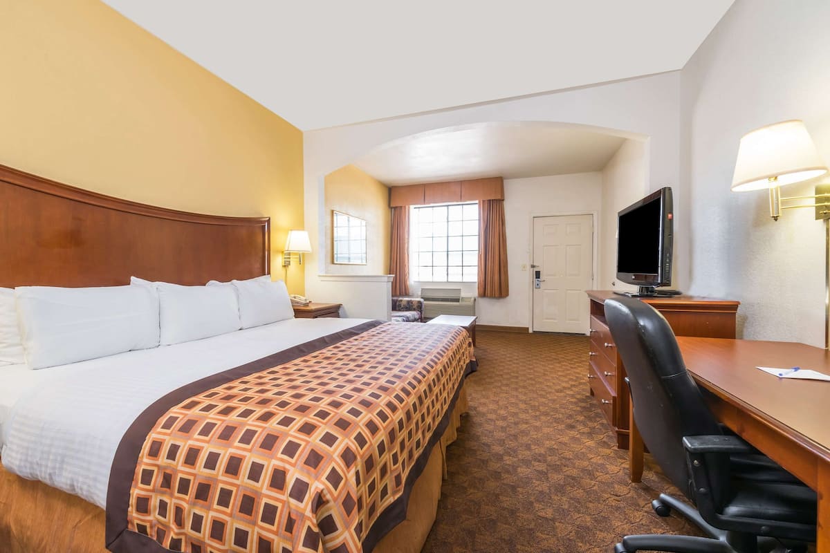 Ein Hotelzimmer mit einem großen Bett, einem Schreibtisch, einem Stuhl, einem Fernseher und einer Schreibtischlampe.