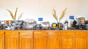 Un comptoir de petit-déjeuner équipé de différents distributeurs de nourriture, d’un appareil à gaufres et d’une machine à café.