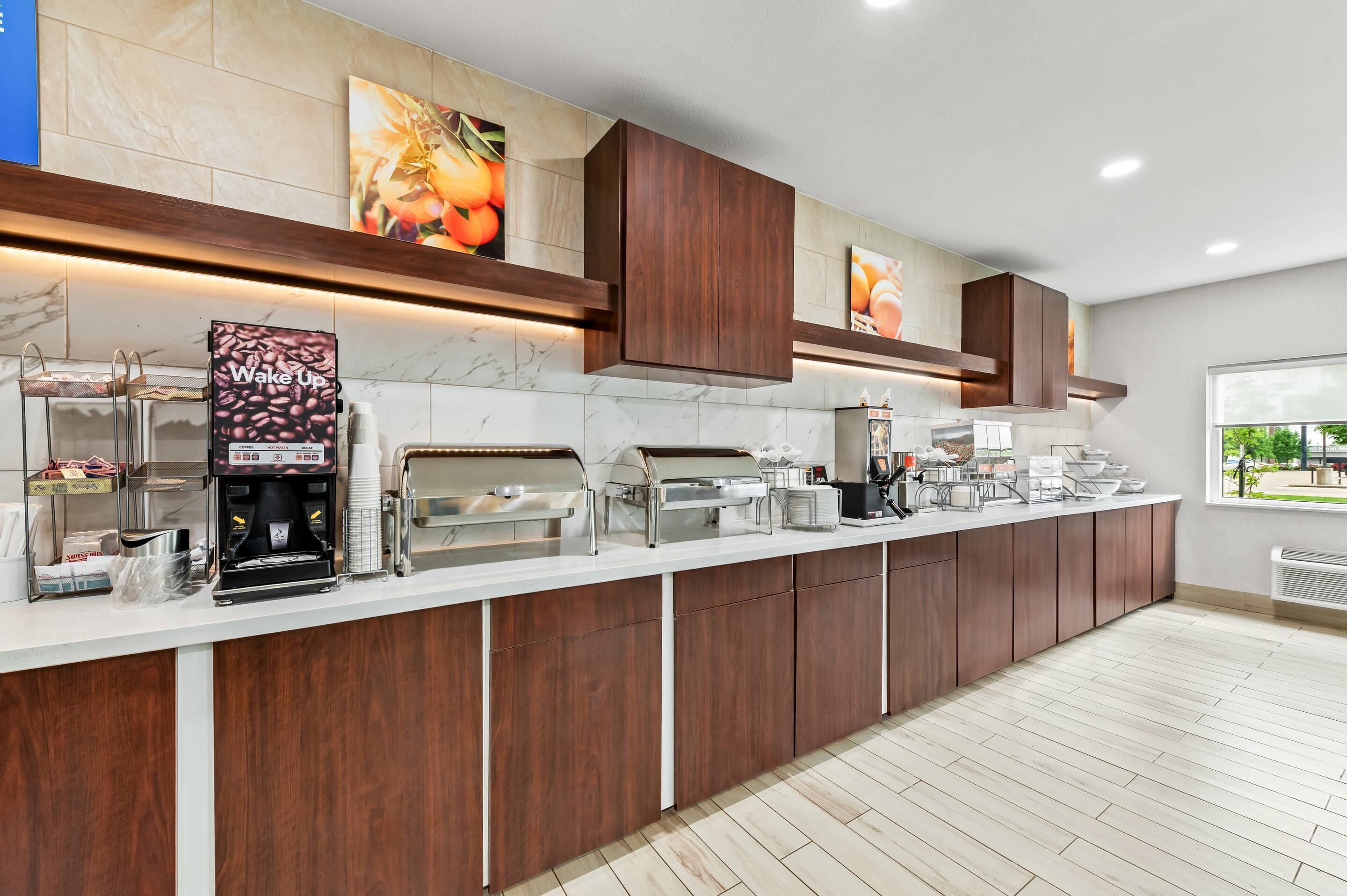 A modern kitchen with a long counter, coffee machines, and a coffee station.
