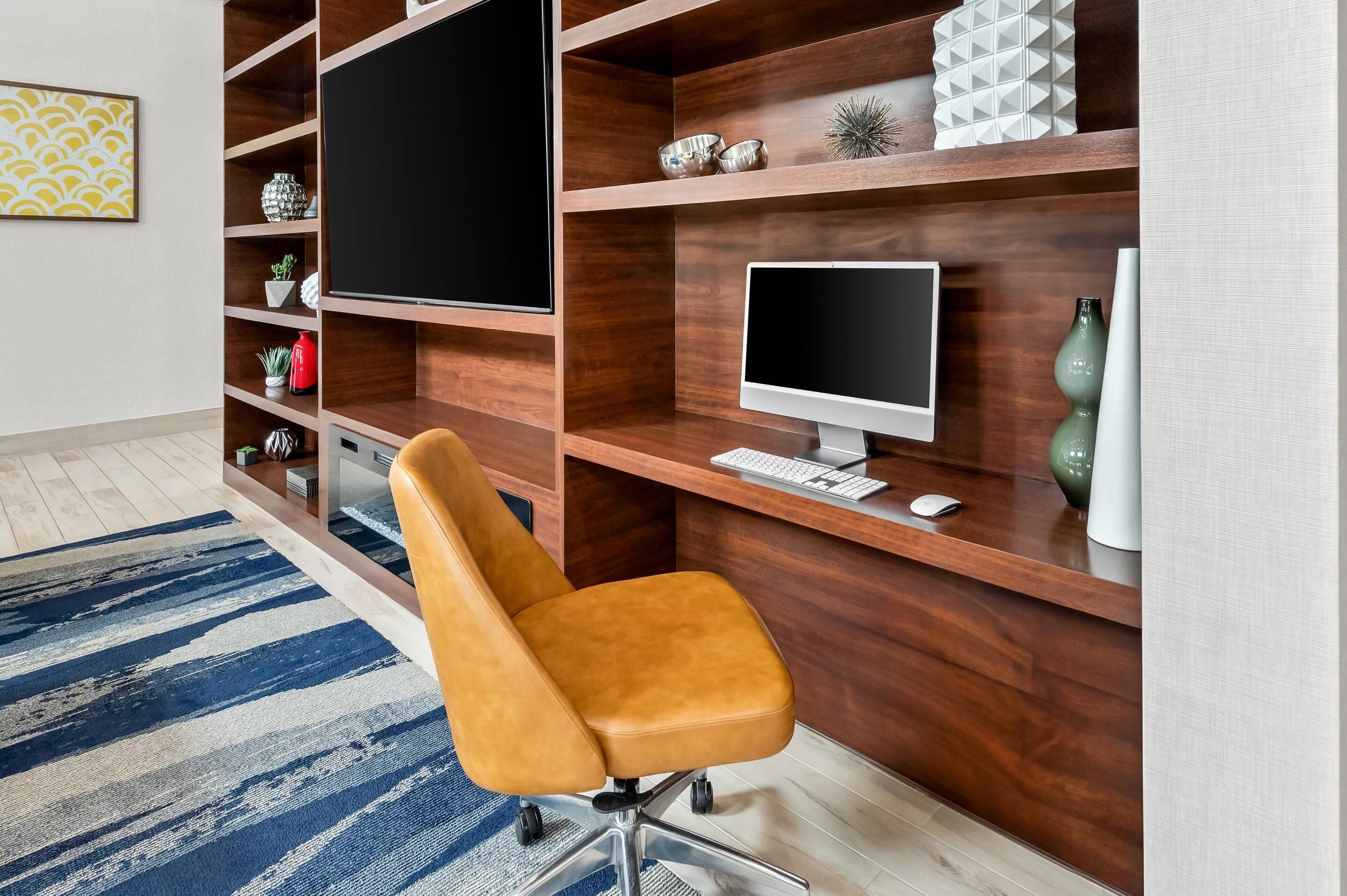 Un espacio de oficina moderno con un escritorio de madera, un monitor de ordenador, un teclado y una silla.