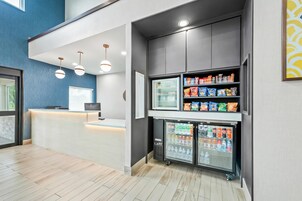 Una moderna zona de recepción con un mostrador, un refrigerador lleno de refrigerios y un dispensador de agua.