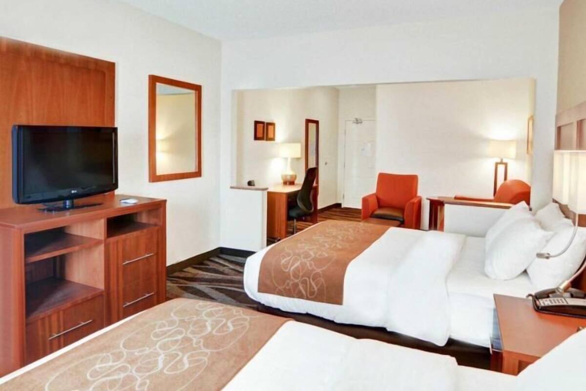 Quarto de hotel com cama, televisão, escrivaninha e cadeira.