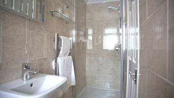 A modern bathroom with a glass-enclosed shower, a white sink, and a mirror above the sink.