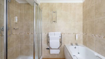 A bathroom with a glass-enclosed shower, a white bathtub, and a towel rack.