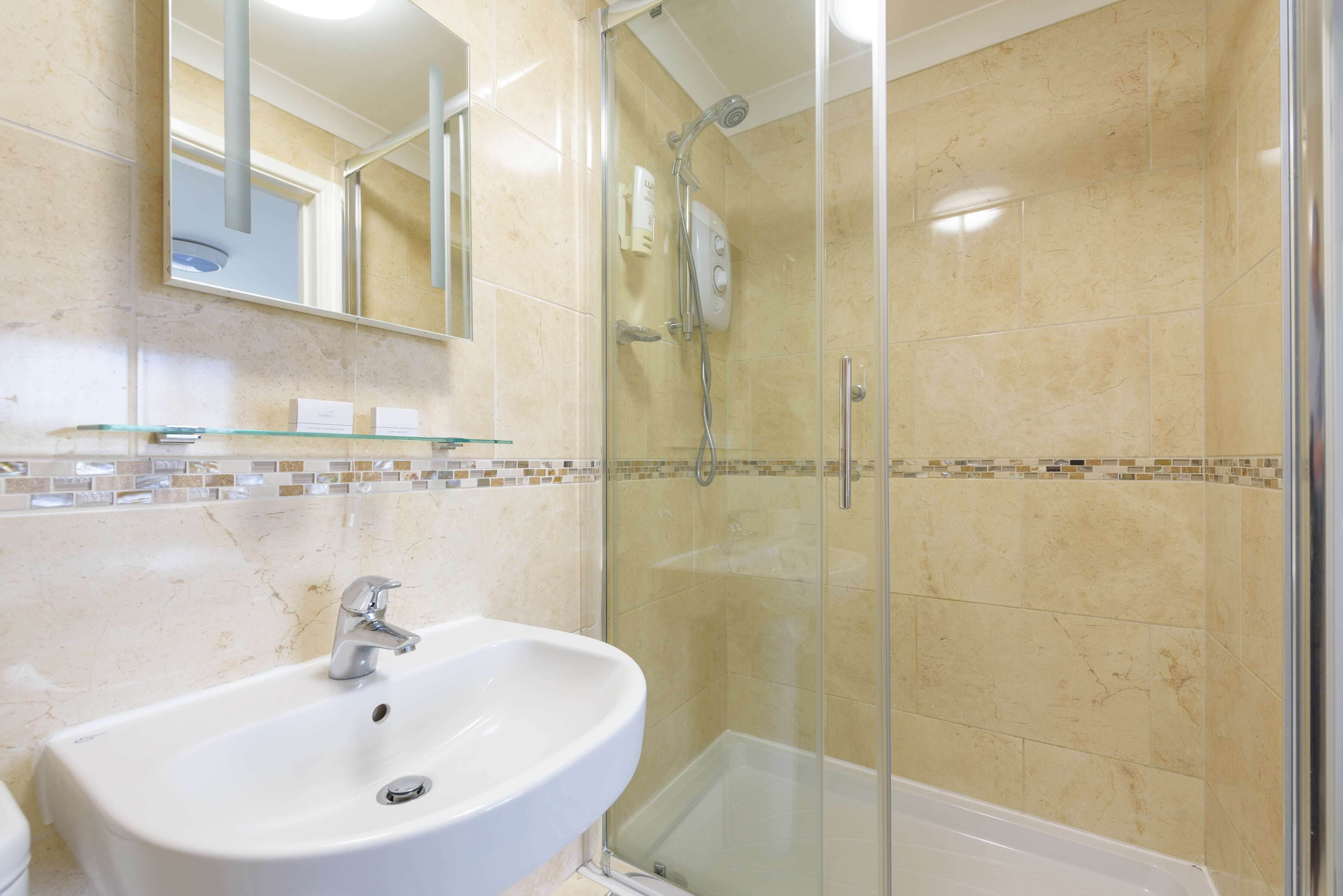 A modern bathroom with a glass-enclosed shower, a white sink, and a tiled backsplash.