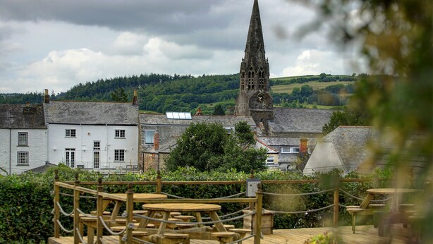 A view of a town with a prominent church tower, surrounded by greenery and buildings. - Best Western Fowey Valley (Lostwithiel)