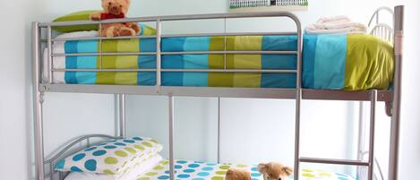A bunk bed with a teddy bear on the top bunk and another on the bottom.