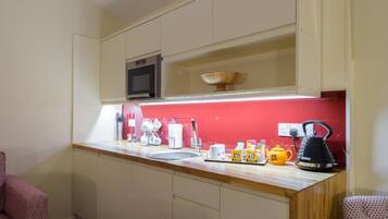 A compact kitchen with a microwave, sink, and various kitchen items on the counter.