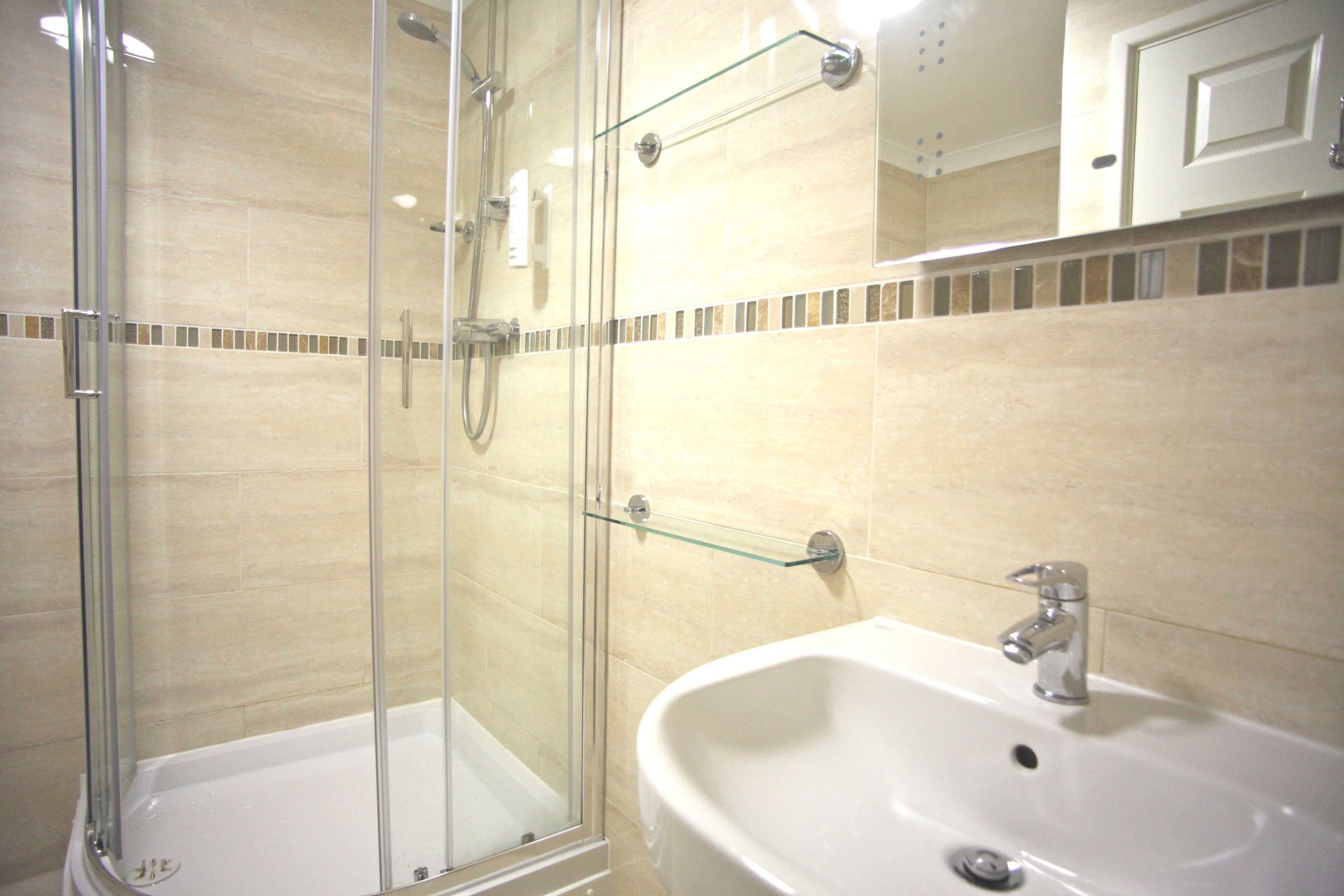Un bagno moderno con doccia vetrata, un lavandino bianco e uno specchio sopra.