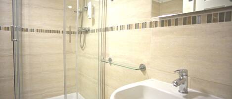Un bagno moderno con doccia vetrata, un lavandino bianco e uno specchio sopra.