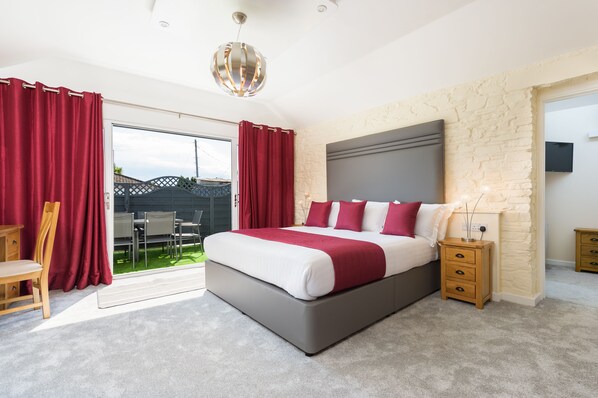 A bedroom with a large bed, a nightstand, a lamp, and a view of the outside.
