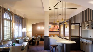 Eine Hotlellobby mit Barbereich, Sitzgelegenheiten und einem großen Gemälde an der Wand.