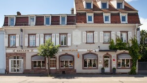 Ein mehrstöckiges Gebäude mit einem Restaurant namens 'Keller' im Erdgeschoss und einem Hotel namens 'Beausejour' in den oberen Stockwerken.
