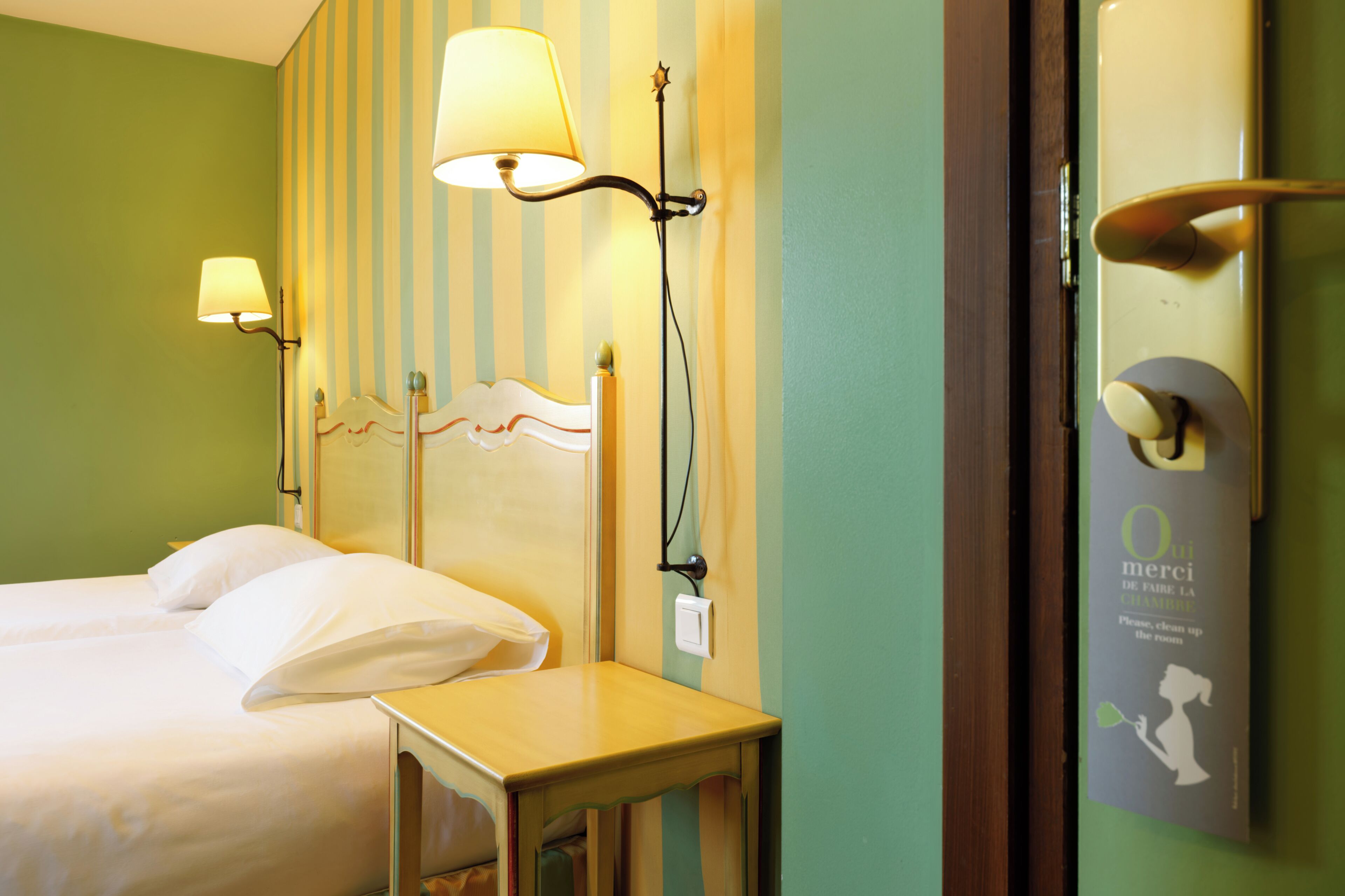 Ein Hotelzimmer mit Bett, Nachttischlampen, einem Nachttisch und einer Wandleuchte.