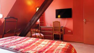 A bedroom with a bed, a desk, a chair, a television, and a door.
