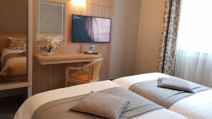A hotel room with two beds, a desk, a TV, and a mirror. - Hotel Champerret Elysees (Paris)
