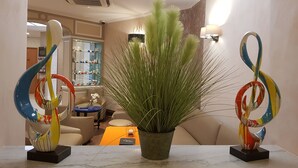 A modern interior with a marble countertop, a potted plant, and abstract sculptures. - Hotel Champerret Elysees (Paris)