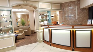 A reception area with a curved counter, seating area, and decorative items. - Hotel Champerret Elysees (Paris)
