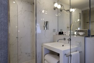 A modern bathroom with a glass-enclosed shower, a white sink, and a large mirror.