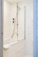 A modern bathroom with a glass-enclosed shower, a white marble floor, and a built-in towel rack.