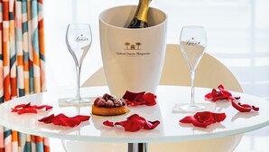 Een tafel met een champagnefles, twee glazen en een dessert op een witte tafelkleed.