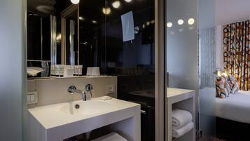 A modern bathroom with a large mirror, two sinks, and a glass shower enclosure.