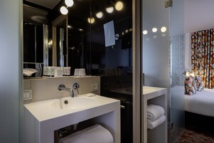 A modern bathroom with a large mirror, two sinks, and a glass shower enclosure.