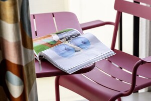 A magazine with a pair of sunglasses on a red chair.