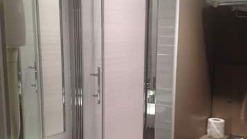 Een moderne badkamer met een douchecabine van glas, een wit wastafelmeubel en een toilet.