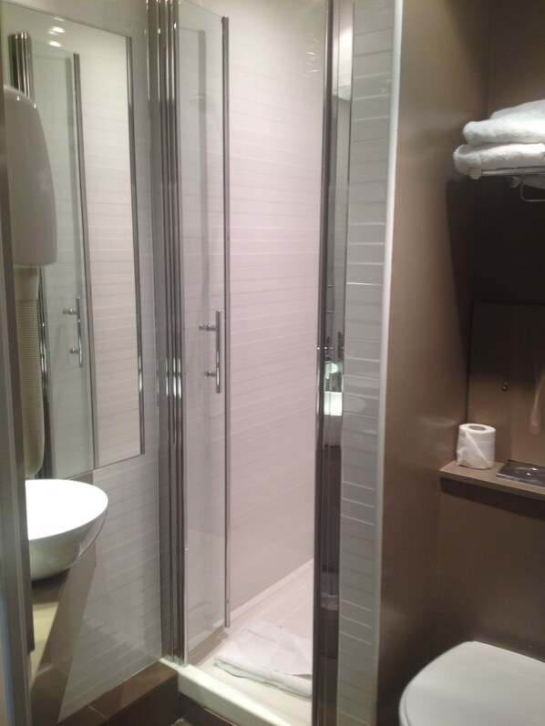 Ein modernes Badezimmer mit einer gläsernen Duschkabine, einem weißen Waschbecken und einer Toilette.