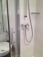 A modern bathroom with a glass-enclosed shower, a white sink, and a chrome faucet.