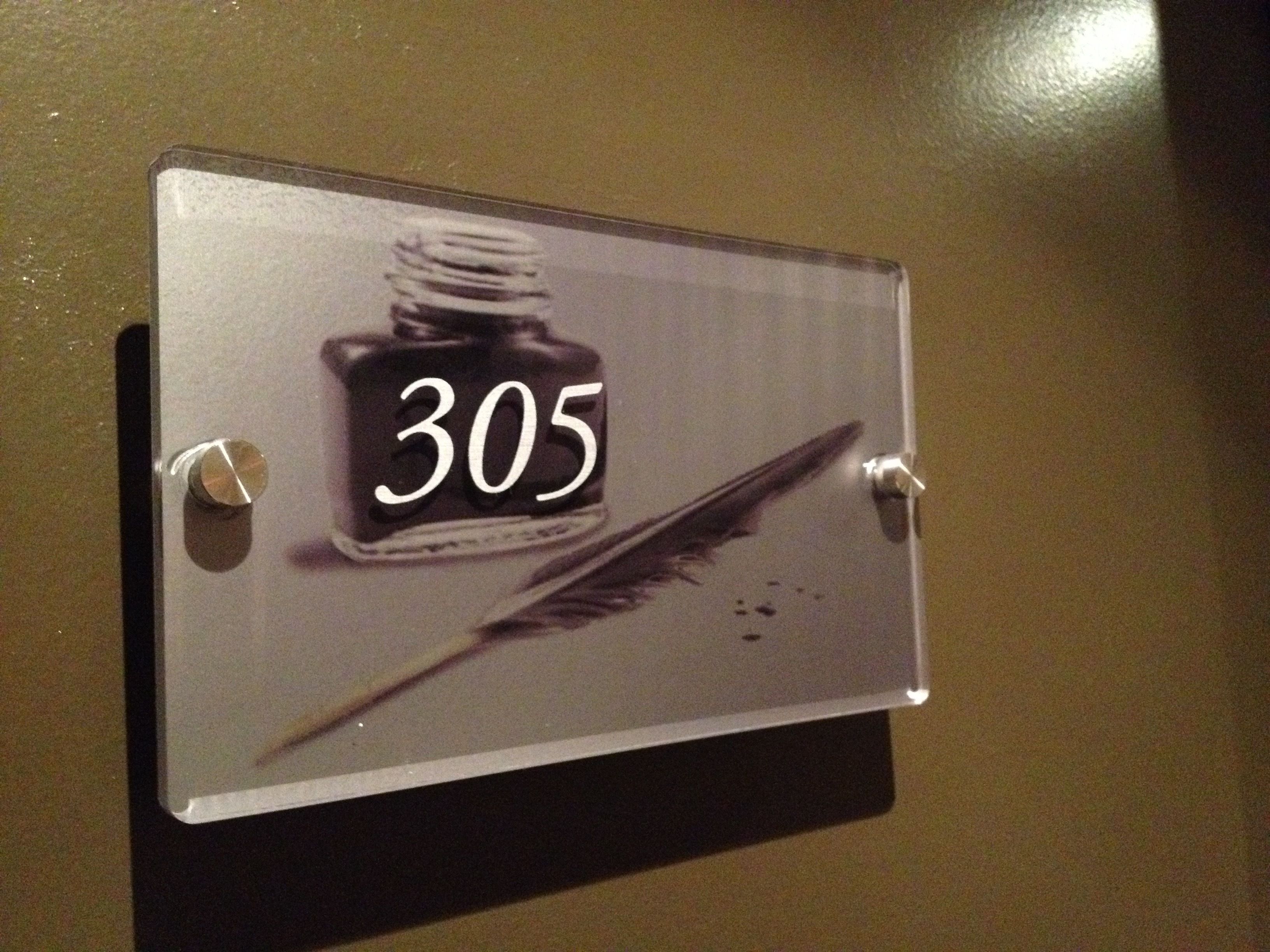Naamplaatje met kamer 305, een ontwerp van veer en inktpot.