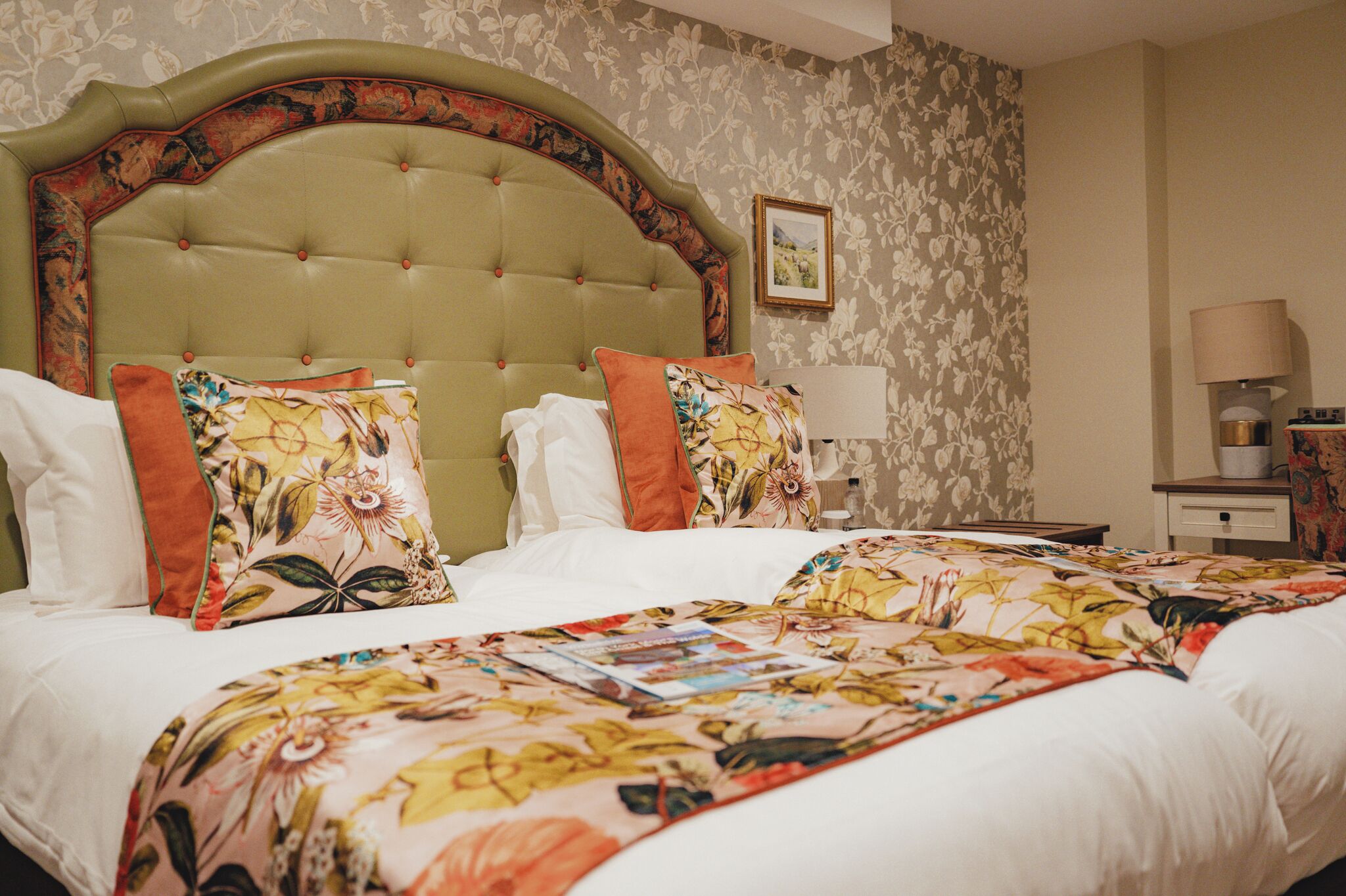 Cama doble con ropa de cama floral y cabecera con arco decorativo.