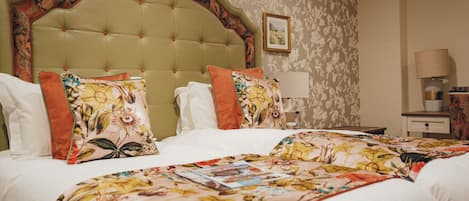 Cama doble con ropa de cama floral y cabecera con arco decorativo.