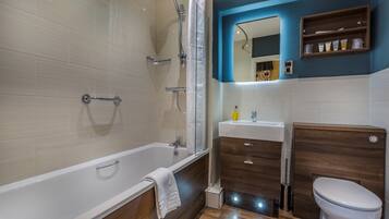 A modern bathroom with a bathtub, shower, vanity, and toilet.