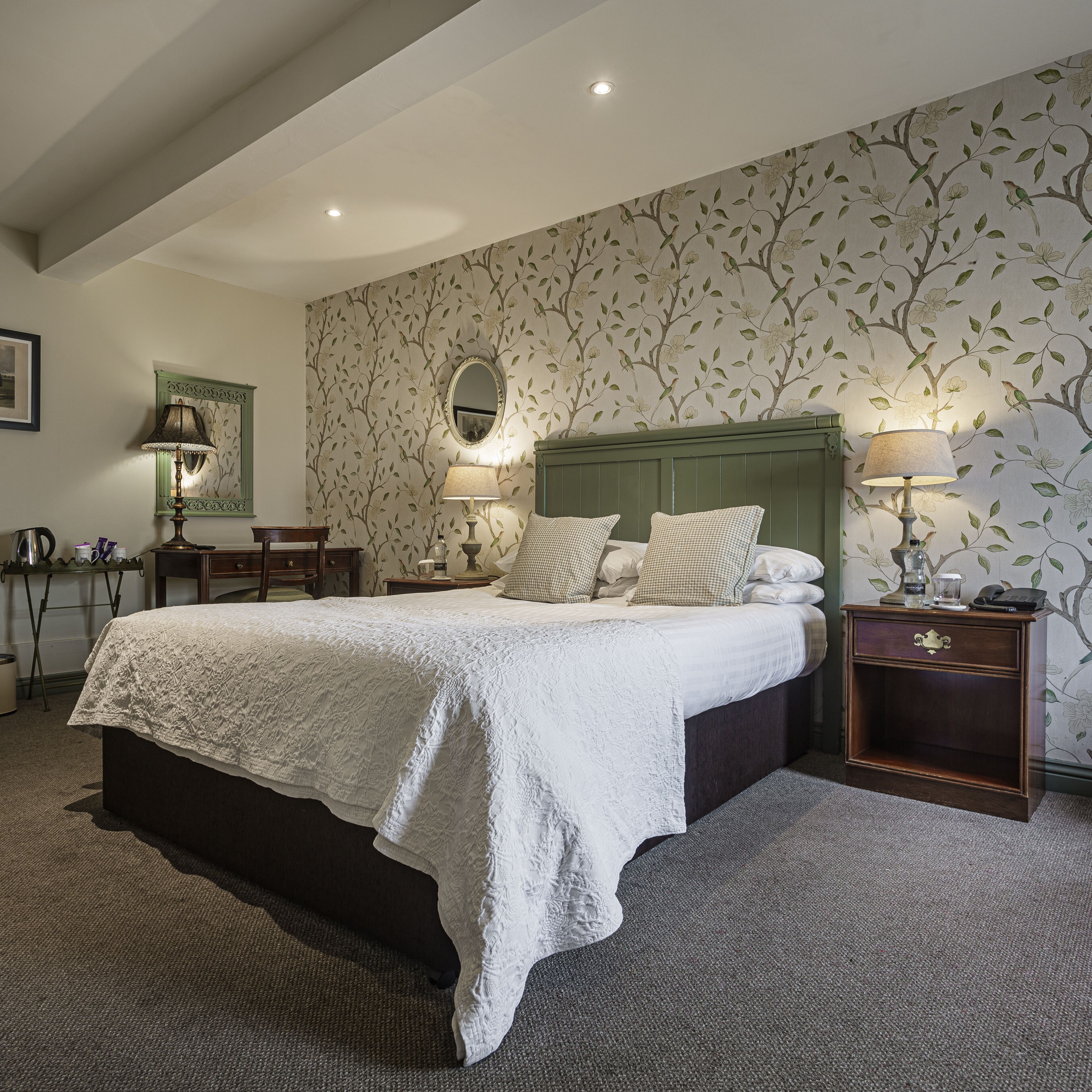 A neatly arranged bedroom with a large bed, two bedside tables, and a mirror.