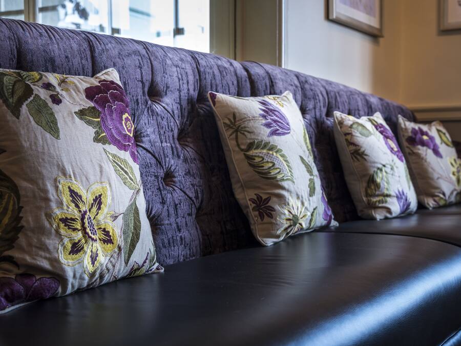 A section of a dark-colored sofa with floral-patterned cushions.