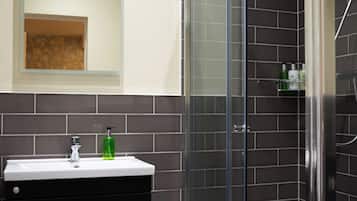 A modern bathroom with a glass shower enclosure, a black vanity with drawers, and a mirror above the sink.