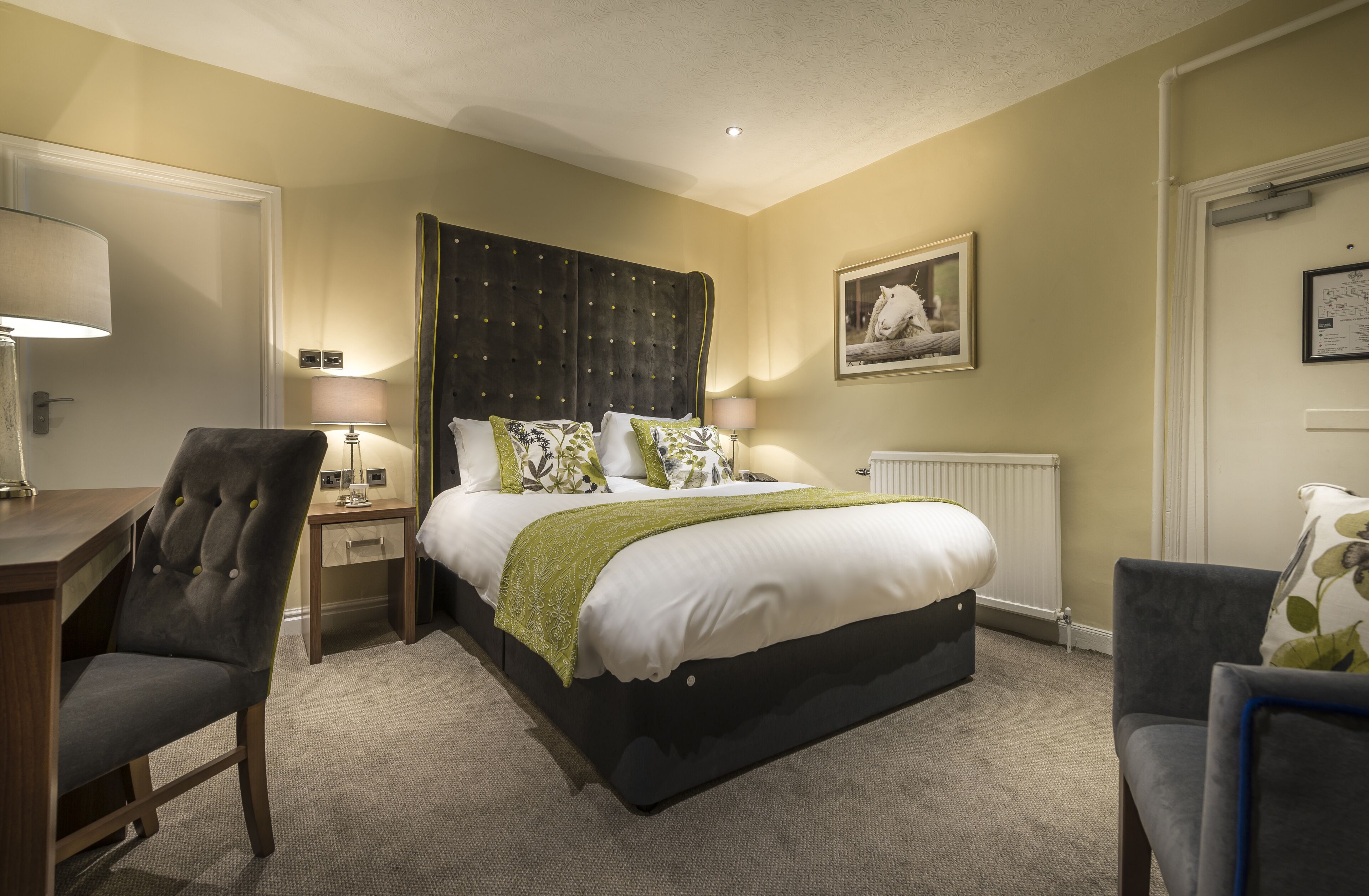 A neatly arranged bedroom with a large bed, bedside tables, a chair, and a radiator.