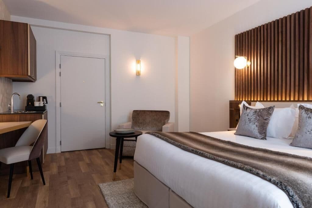 A hotel room with a bed, a desk, a chair, and a small table.