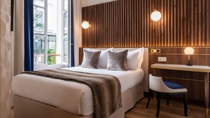 A modern bedroom with a large bed, a desk, and a chair. - Hotel Lord Byron (Paris)