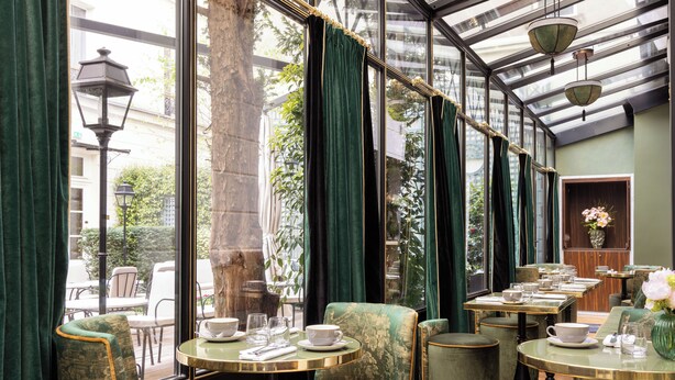 A restaurant with green upholstered chairs and tables, large windows with curtains, and hanging lamps. - Hotel Lord Byron (Paris)