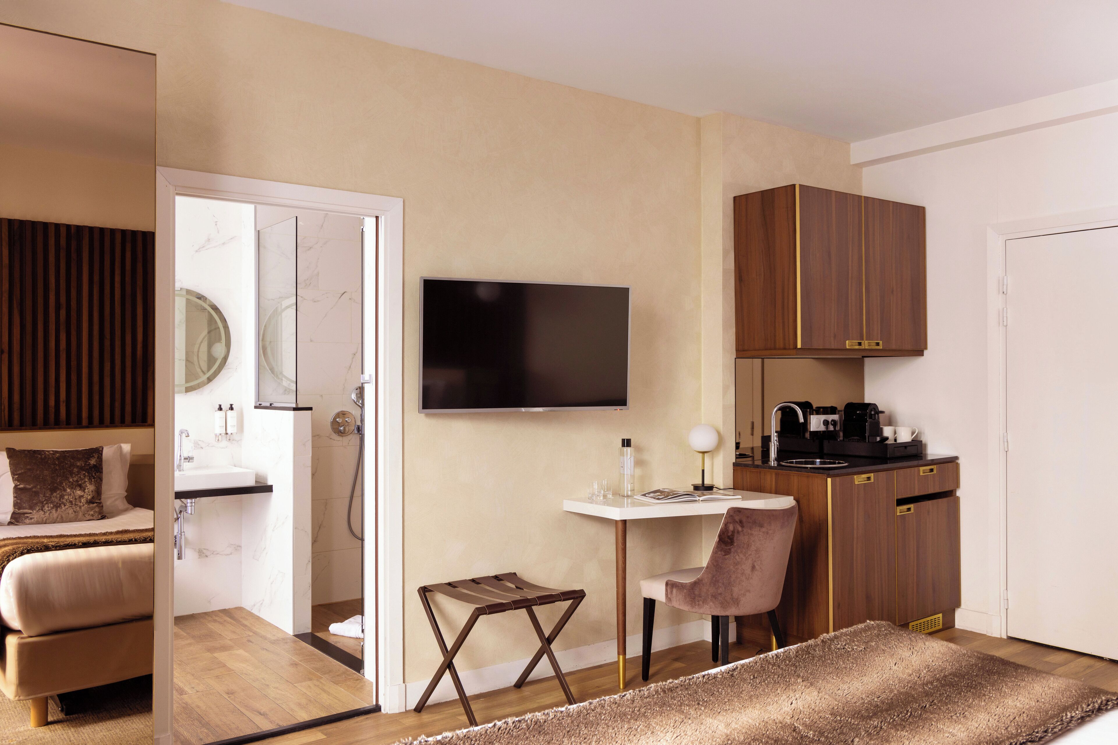 Habitación de hotel moderna con cama, escritorio, silla, televisión, baño y kitchenette.