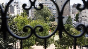 A view through ornate metalwork, featuring a tree-lined street with multi-story buildings in the background. - Hotel Moulin Vert (Paris)