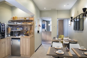 Enjoy a meal in a warm and inviting dining area with tables set and a fully equipped kitchen nearby.