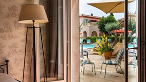 A hotel room with a view of an outdoor pool area, including lounge chairs and umbrellas. - Best Western l'Orangerie (Nîmes)