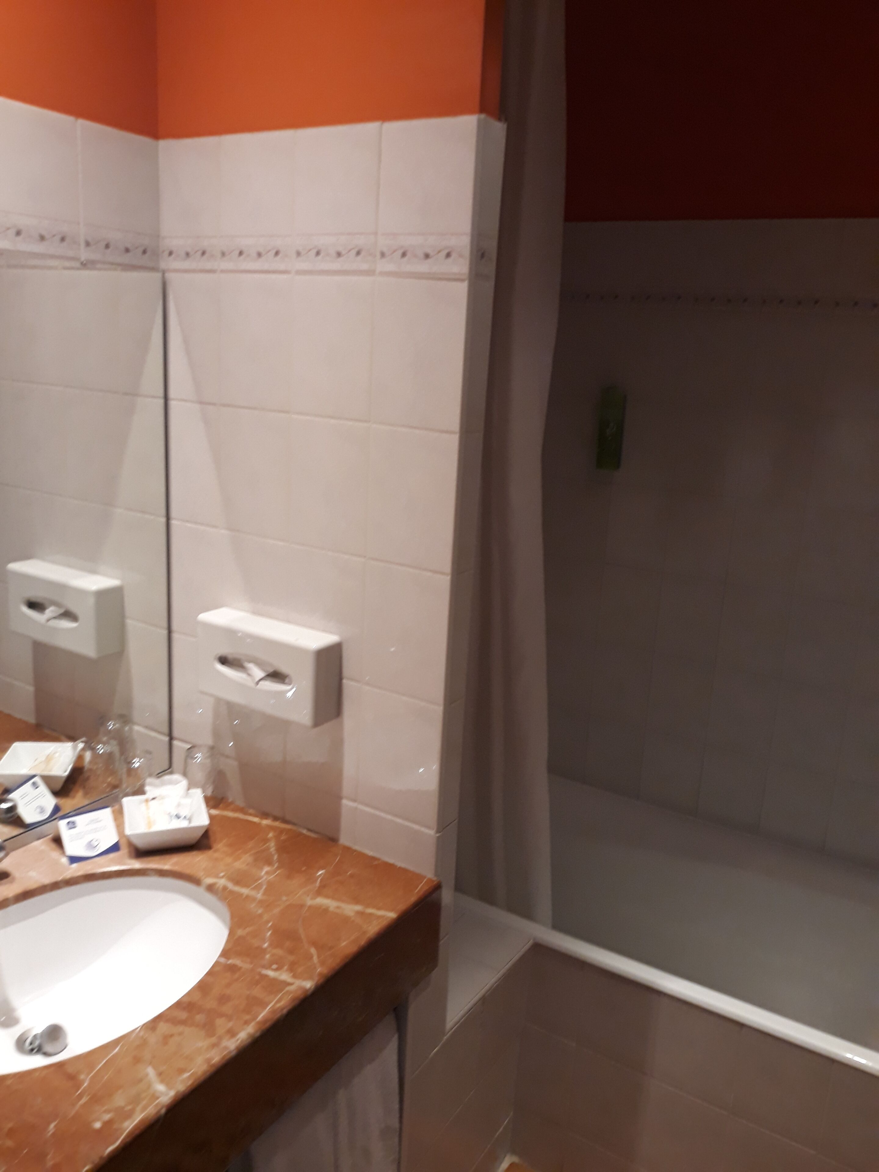 A bathroom with a marble sink, a mirror, a towel rack, and a shower area.