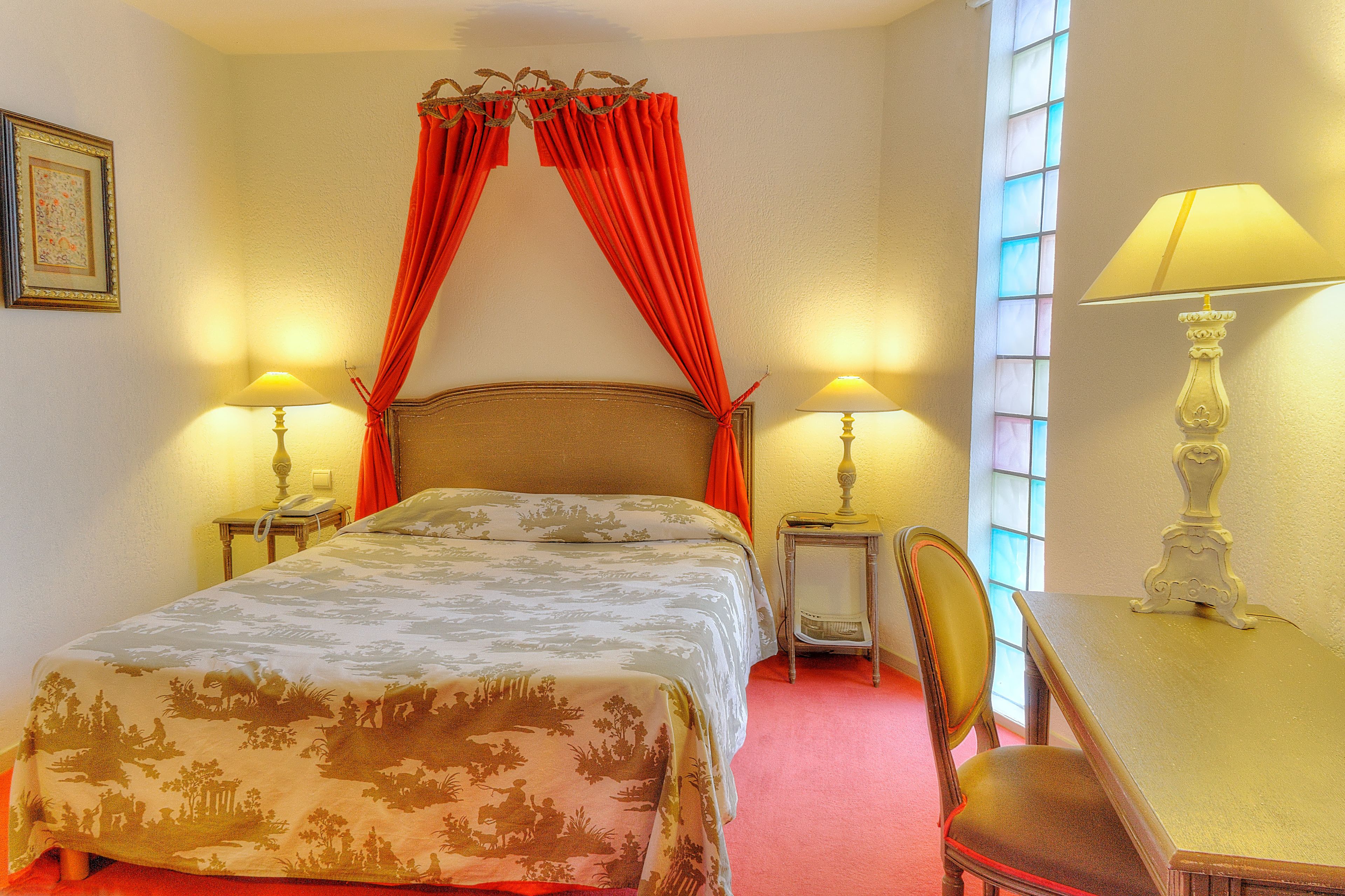 Une chambre d’hôtel comprenant un lit, deux tables de chevet avec des lampes, une chaise et une fenêtre avec des rideaux.