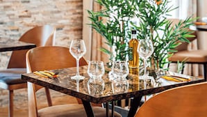 A dining table set with wine glasses, a bottle, and cutlery, with chairs around it. - Best Western l'Orangerie (Nîmes)